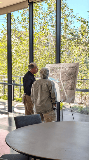 Two men analyze a city stormwater map indoors.